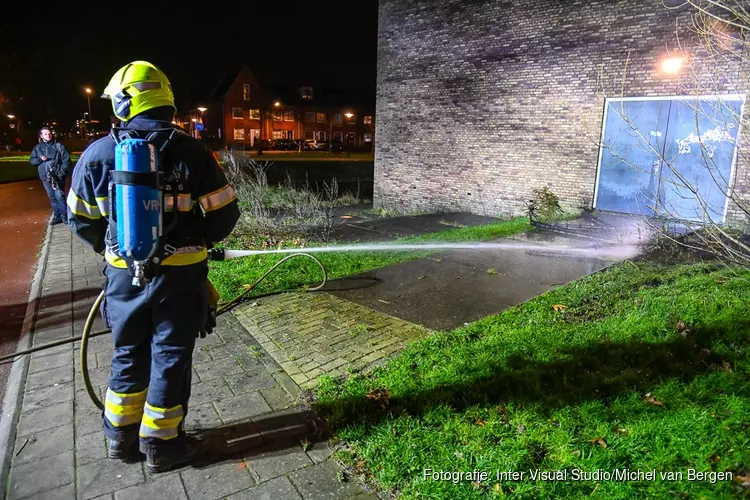 Stapel kerstbomen in brand tegen sporthal in Broekpolder